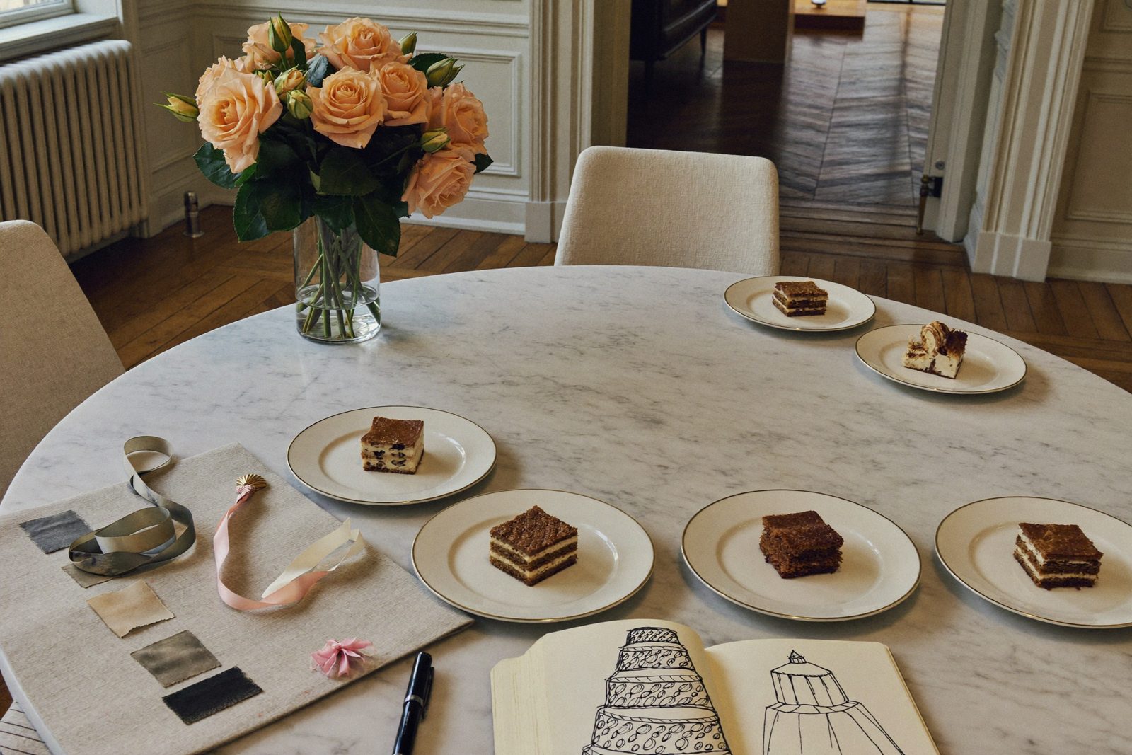 A private tasting in the Tribeca salon with six slices of cake, ribbon samples and a sketchbook on a marble table