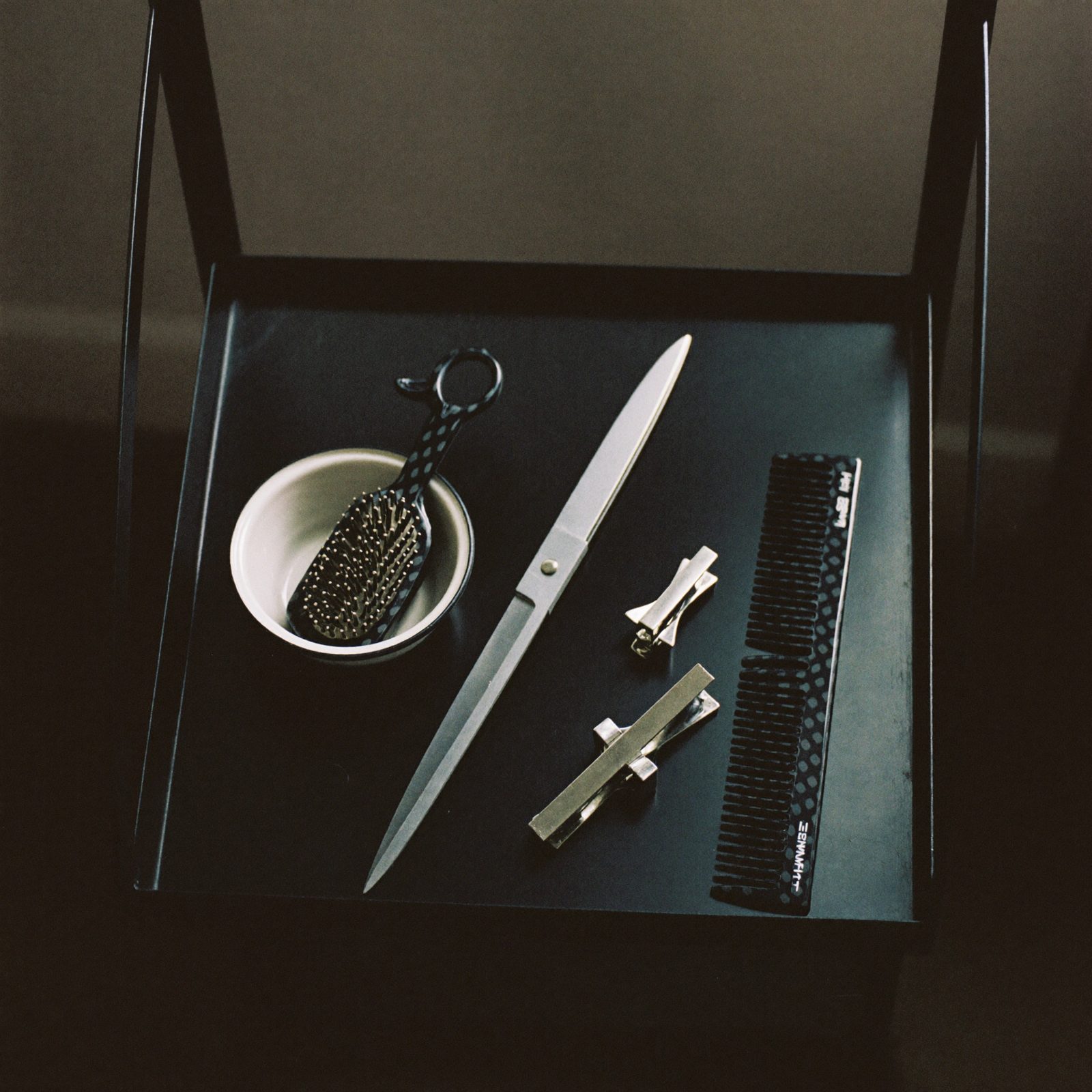 Cutting shears, comb and a tint bowl on a steel tray